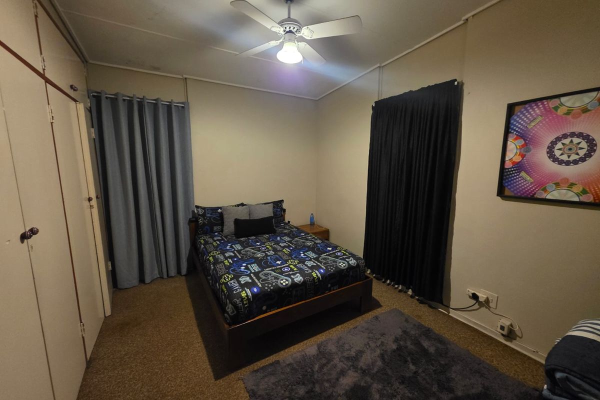 A functional bedroom featuring built-in storage cabinetry, a ceiling fan, and neutral wall finishes.