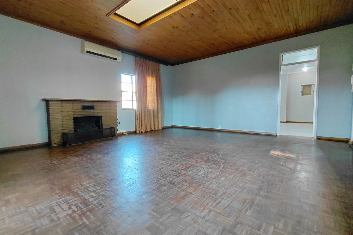 Spacious living room featuring a wood-paneled ceiling with skylight, parquet flooring, a brick fireplace, and a wall-mounted air conditioning unit.