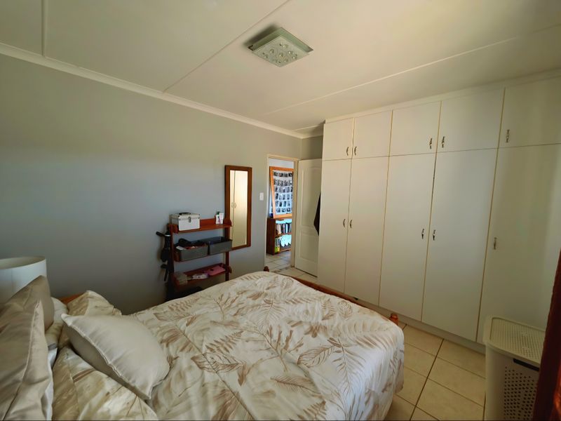 A bedroom featuring built-in white cabinetry, tiled flooring, and a central ceiling light fixture.