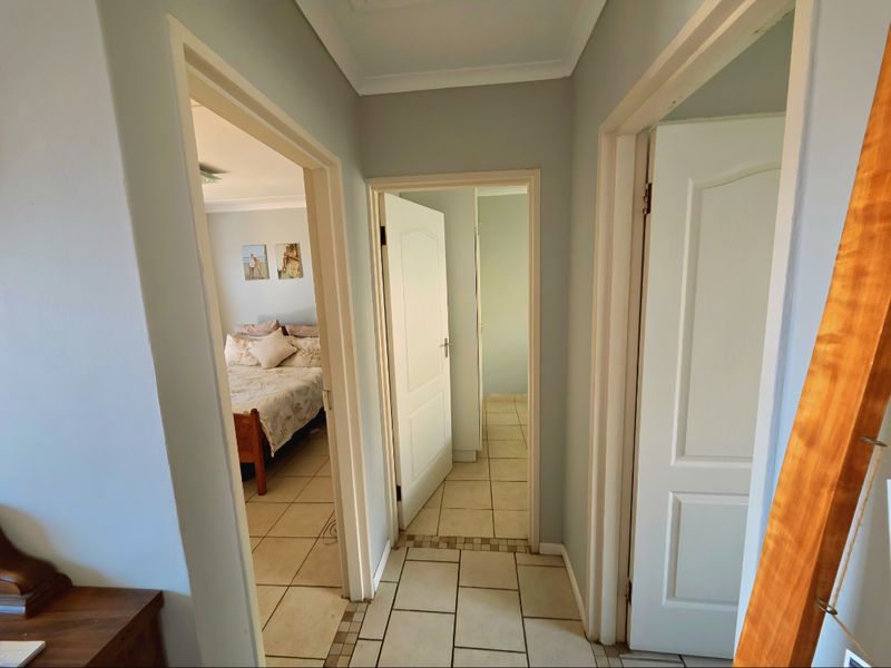 A view from the hallway looking into a bedroom and an adjacent room, featuring tiled flooring and interior doors.