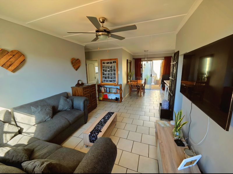 Open-plan living and dining area featuring tiled flooring, a ceiling fan, and sliding glass doors leading to an outdoor patio space.