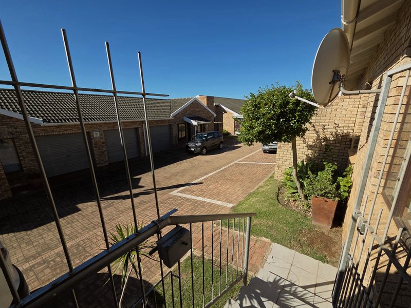 View of the townhouse complex driveway, featuring paved parking areas, multiple garage doors, and established brick exterior walls.