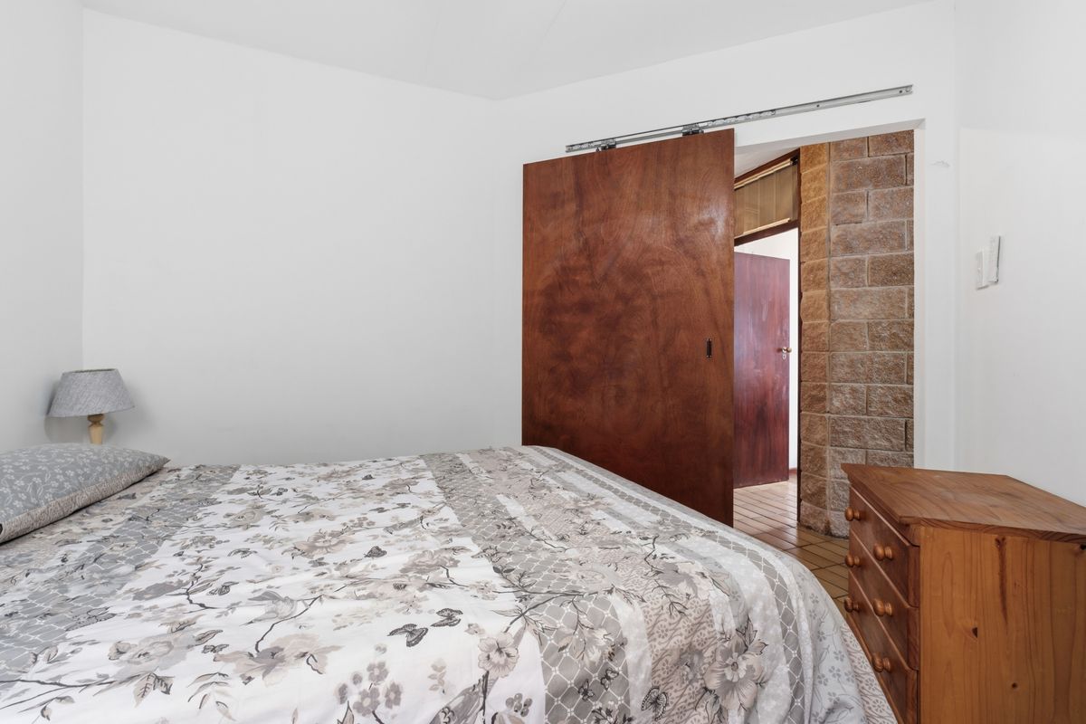 A bedroom featuring a sliding wooden door and exposed brickwork detail, providing a rustic architectural element to the space.