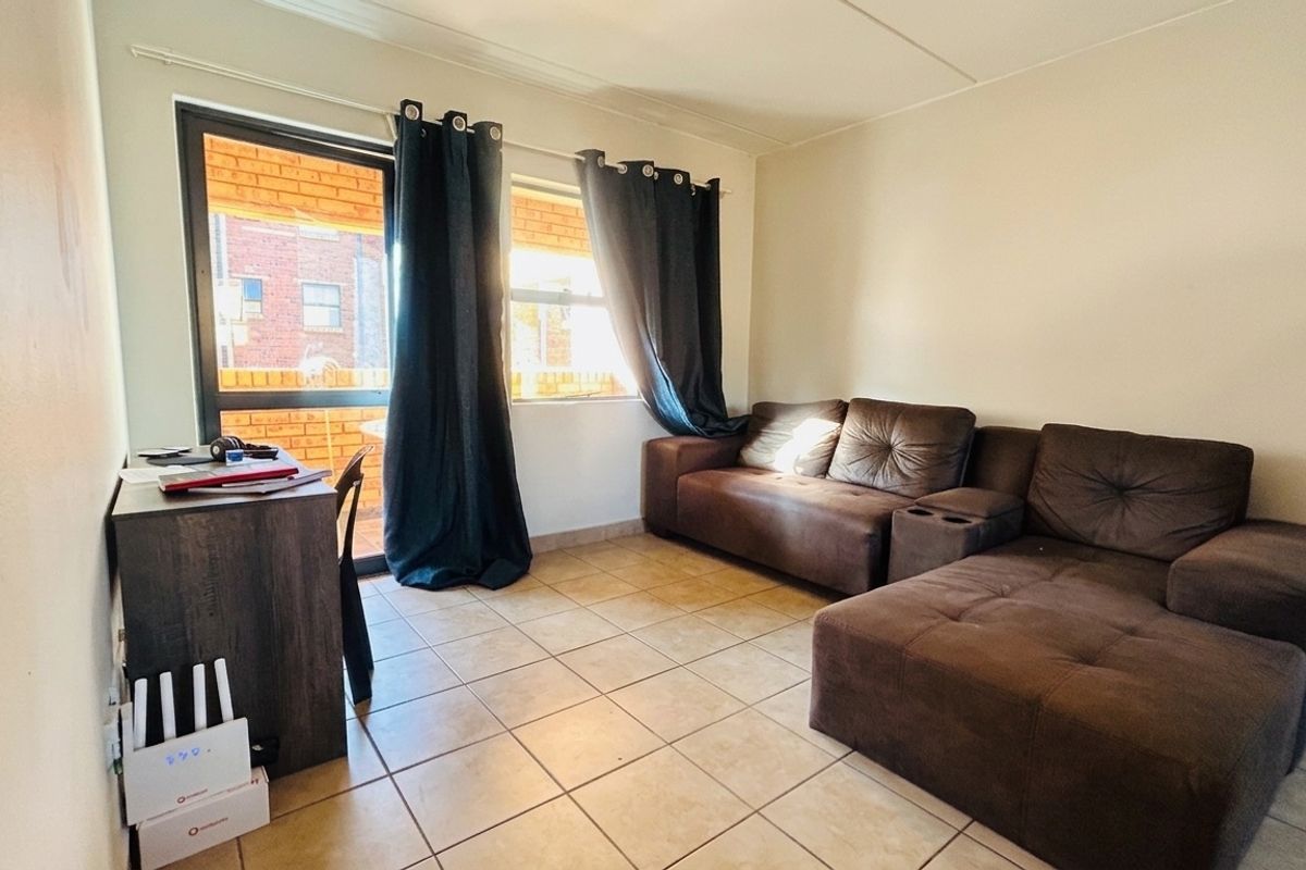 A functional living room featuring tiled flooring and a sliding glass door providing access to an outdoor area.