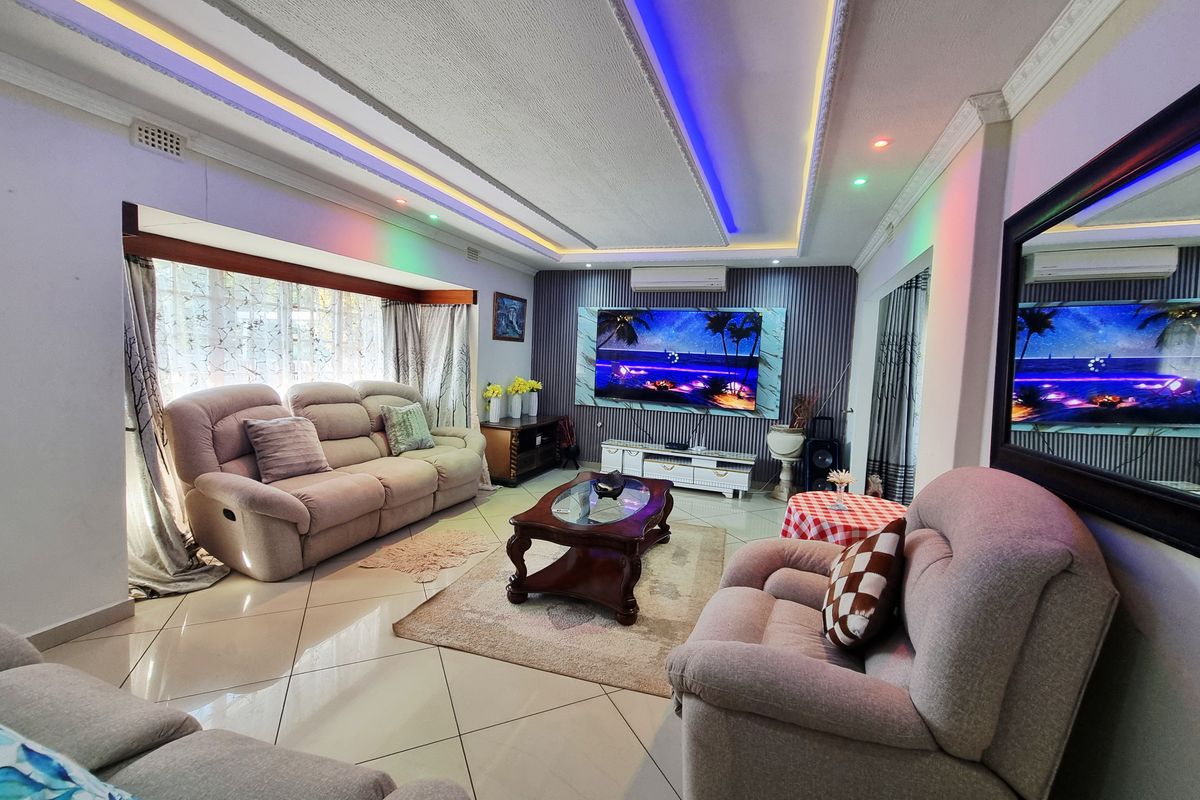 Spacious living room featuring tiled flooring, decorative recessed ceiling with integrated LED lighting, and a wall-mounted air conditioning unit.