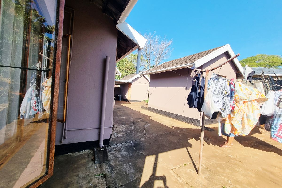 Exterior view of the property showing the rear paved courtyard area between building structures with exposed drainage pipes.