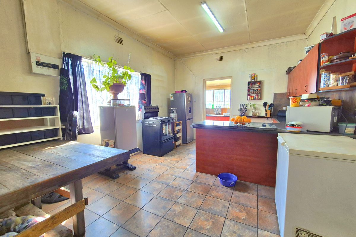 A dated kitchen featuring tiled flooring, wooden cabinetry, and a central breakfast bar, requiring cosmetic updates to modernize the space.