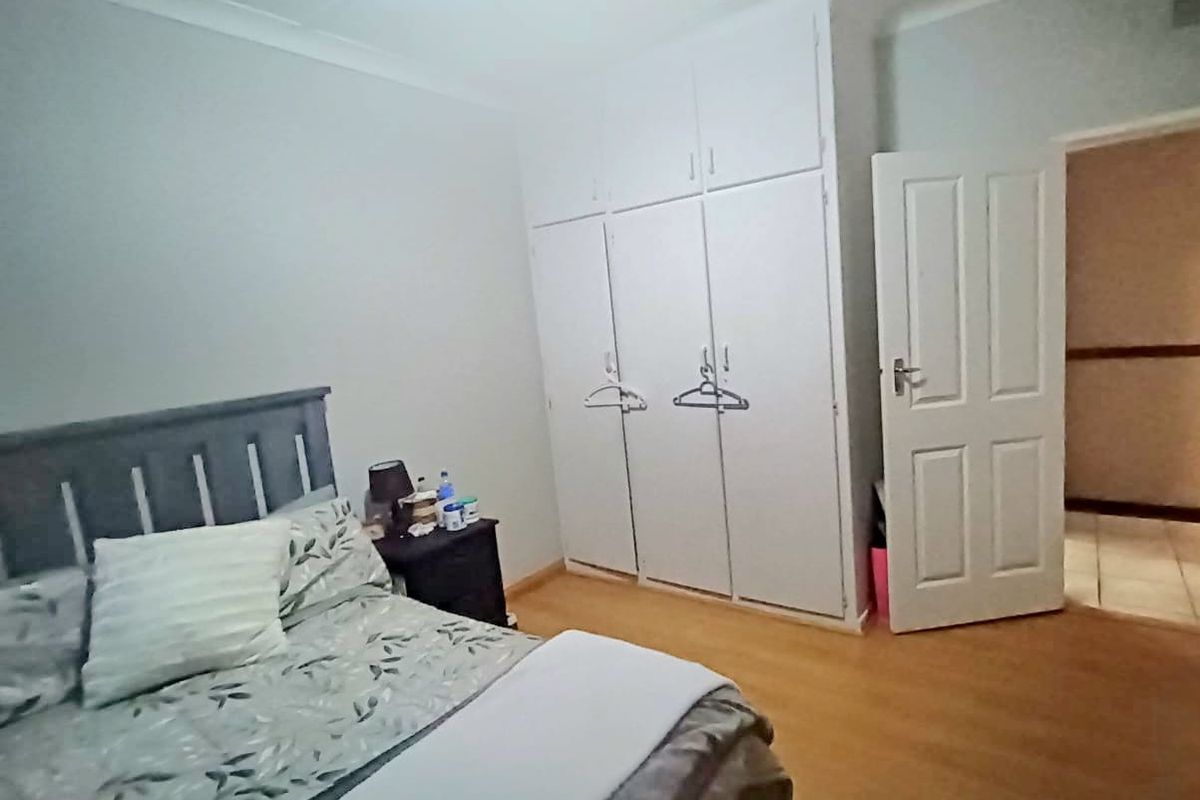 A bedroom featuring built-in cupboards and laminate flooring, providing functional storage and a neutral living space.