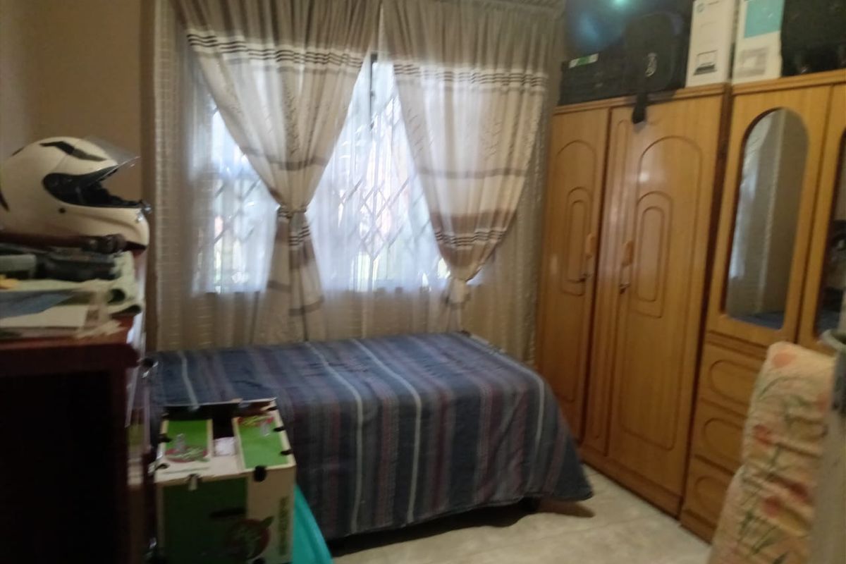 A bedroom featuring built-in wooden wardrobes and a window with security bars.