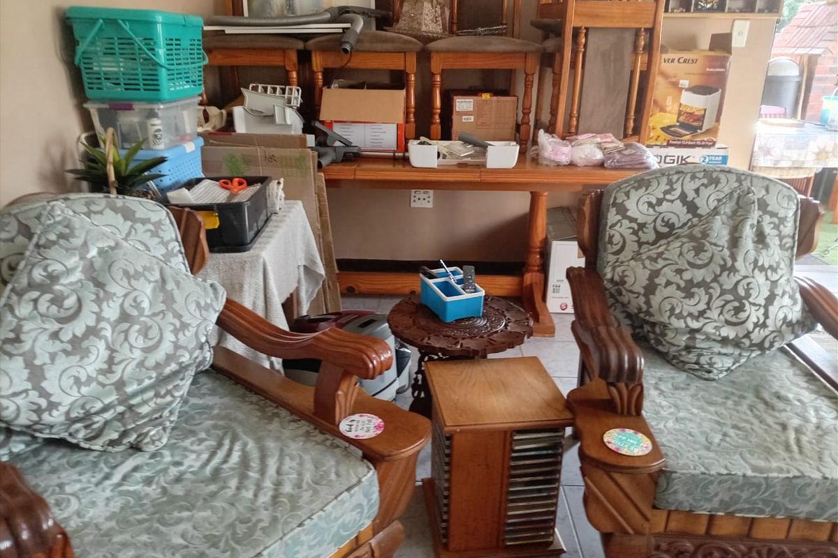 A living area featuring tiled flooring, currently used for storage with various household items present.