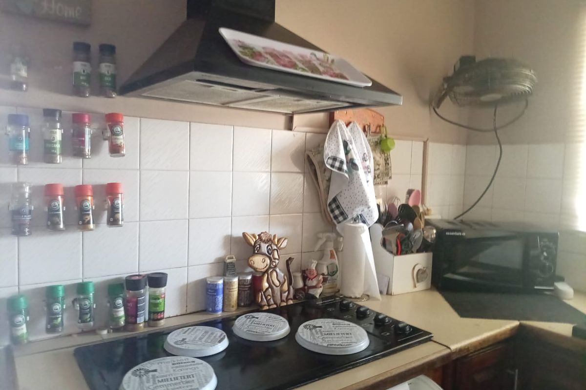 A functional kitchen workspace featuring a built-in electric hob, extractor fan, and tiled backsplash with ample counter space for food preparation.