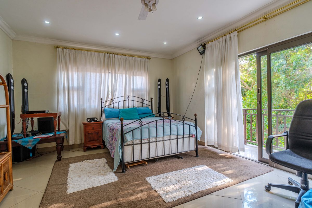 Spacious bedroom featuring tiled flooring, recessed ceiling lighting, and large sliding glass doors providing direct access to a private balcony.