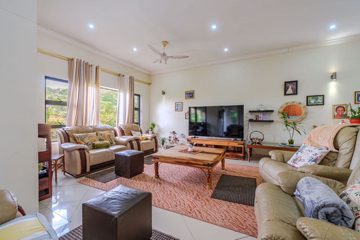 Spacious living room featuring tiled flooring, recessed ceiling lighting, a ceiling fan, and large windows allowing for natural light.