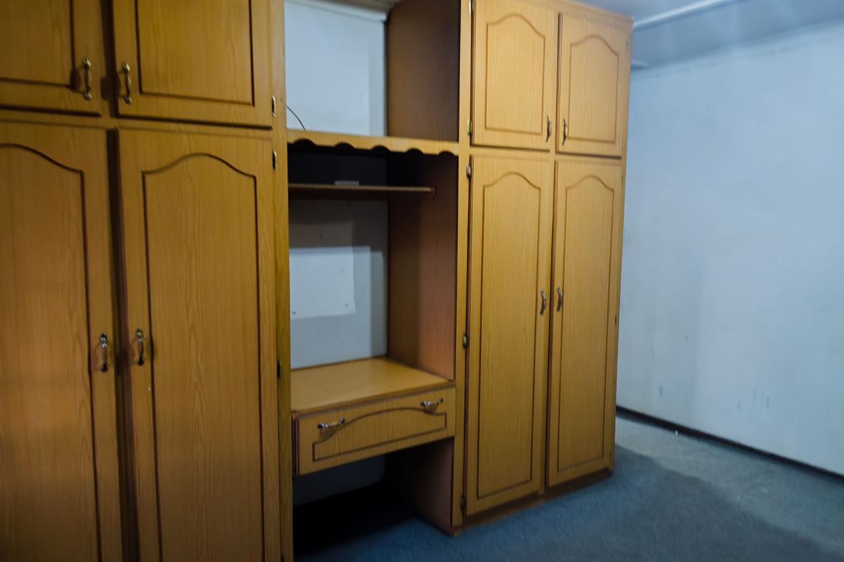 A bedroom featuring extensive built-in wooden cabinetry with integrated shelving and desk space, providing ample storage and functional utility.