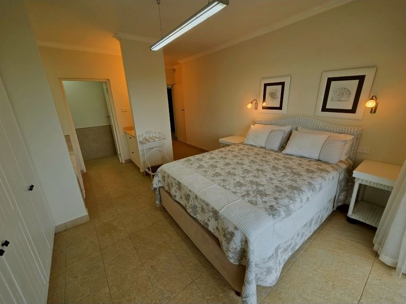 A well-lit bedroom featuring tiled flooring, built-in cupboards, and an en-suite bathroom access point.