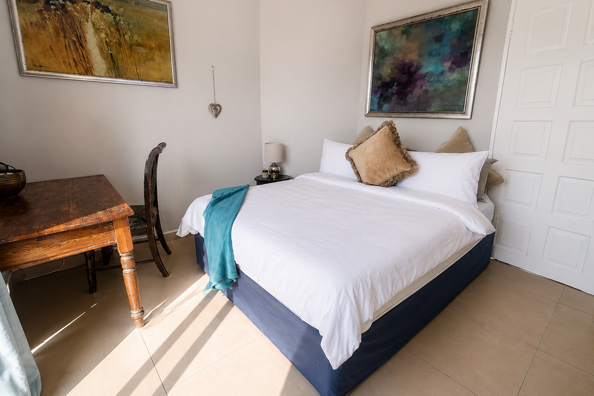 A well-lit bedroom featuring neutral wall tones, tiled flooring, and a classic panelled door, providing a comfortable and functional living space.