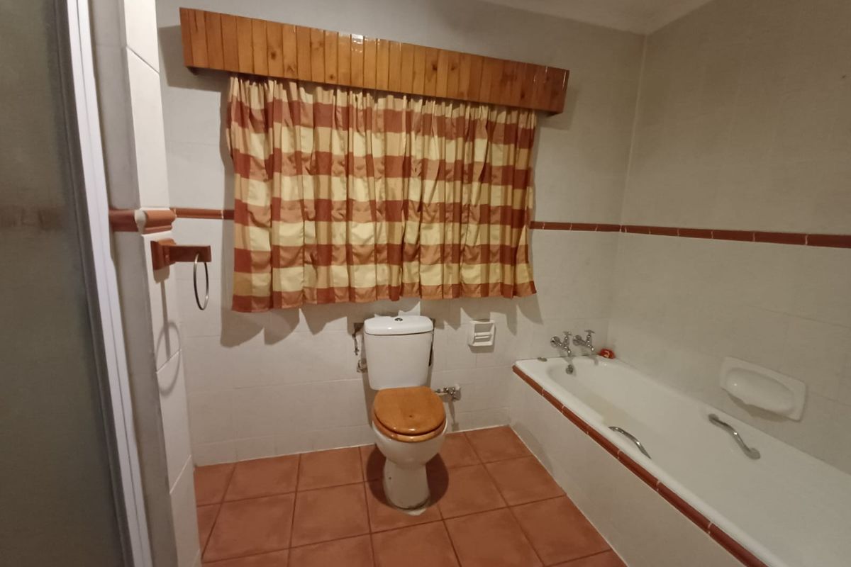 A functional bathroom featuring a built-in bathtub, a standard toilet, and tiled flooring with a classic layout.