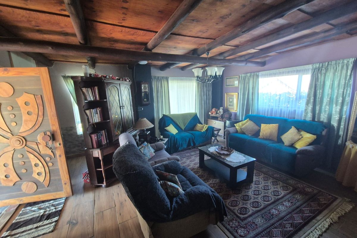 A cozy living room featuring exposed timber ceiling beams, wood-look flooring, and a decorative solid wood entrance door.
