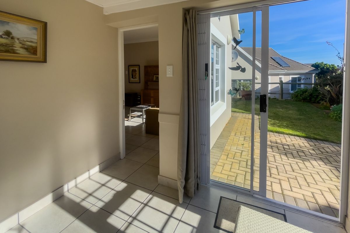A bright interior space featuring tiled flooring and sliding glass doors that open onto a paved patio and garden area.