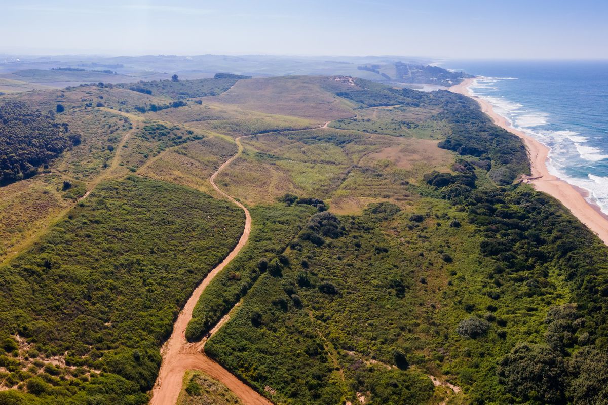 An expansive aerial view of a large coastal residential land parcel featuring natural vegetation, rolling terrain, and direct proximity to the ocean coastline.
