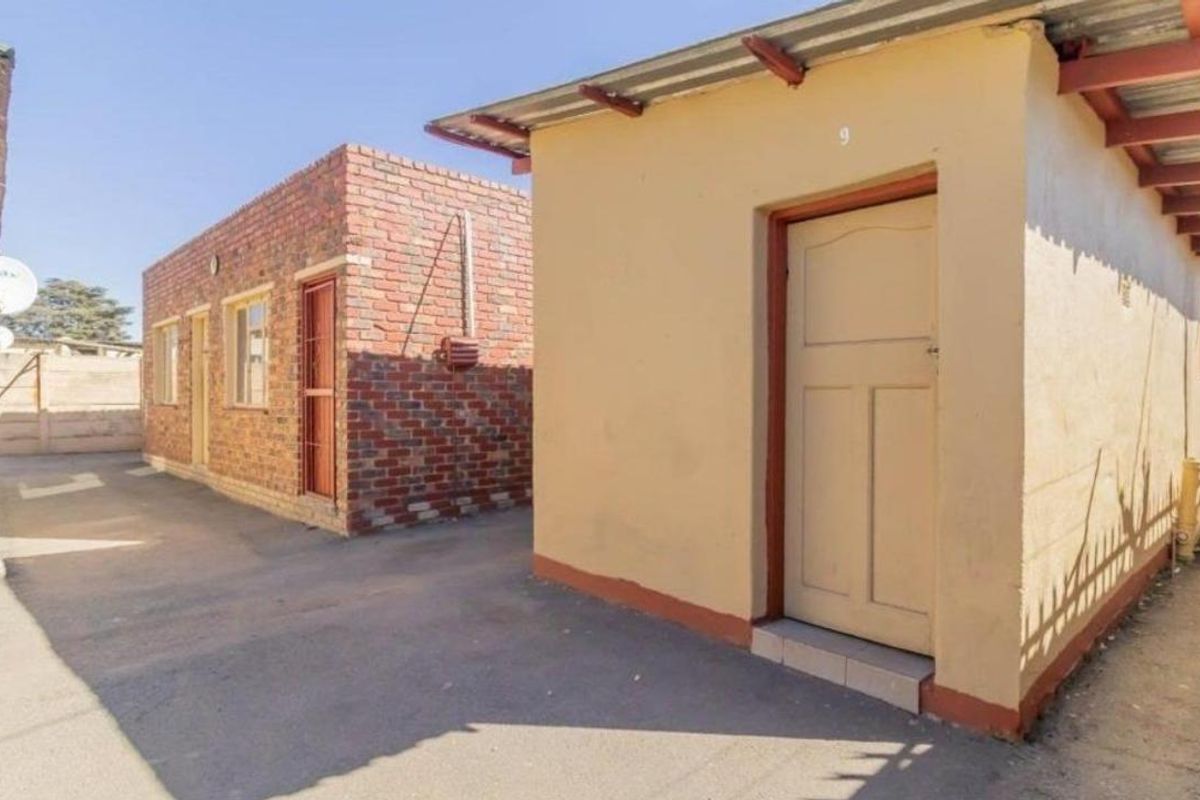 Exterior view of outbuildings featuring brick and plastered masonry construction with corrugated metal roofing and secure access doors.