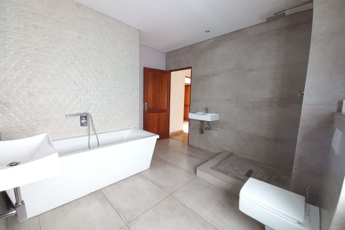 Modern bathroom featuring a freestanding bathtub, wall-mounted basin, walk-in shower with grey tiling, and a wall-hung toilet.