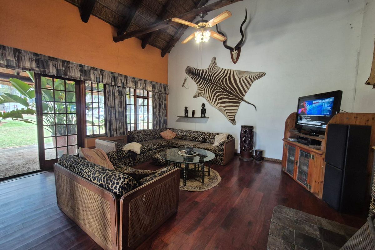 Spacious living room featuring high vaulted thatched ceilings, dark wood flooring, and large glass sliding doors providing access to the outdoor area.