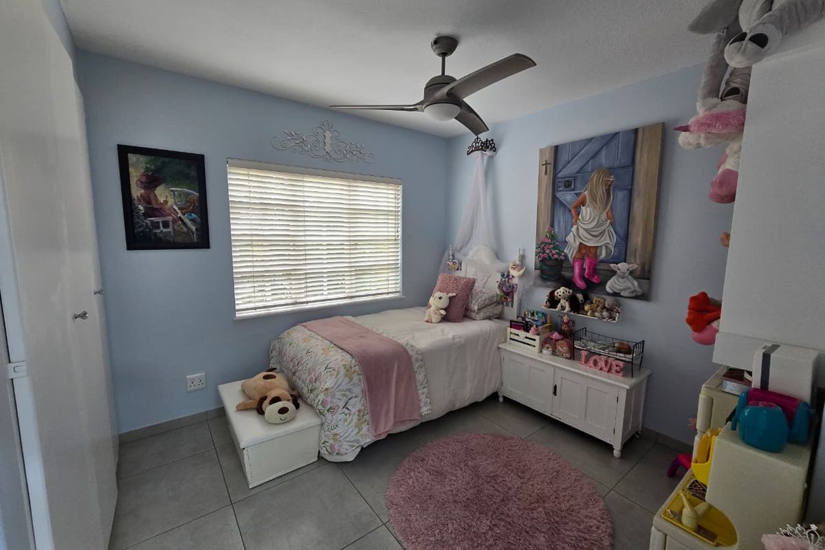 A well-maintained bedroom featuring neutral floor tiles, a ceiling fan, and built-in cupboard storage.