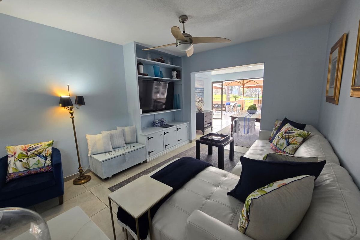 A comfortable living room featuring built-in cabinetry, a ceiling fan, and large sliding doors that open onto a patio area.