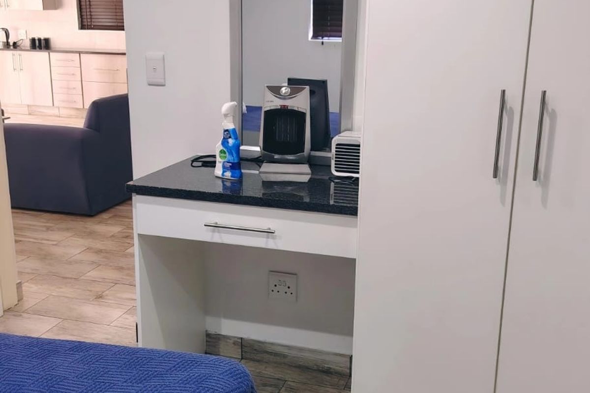 Bedroom featuring a built-in wardrobe and a vanity station with a granite countertop, finished with modern tiled flooring.