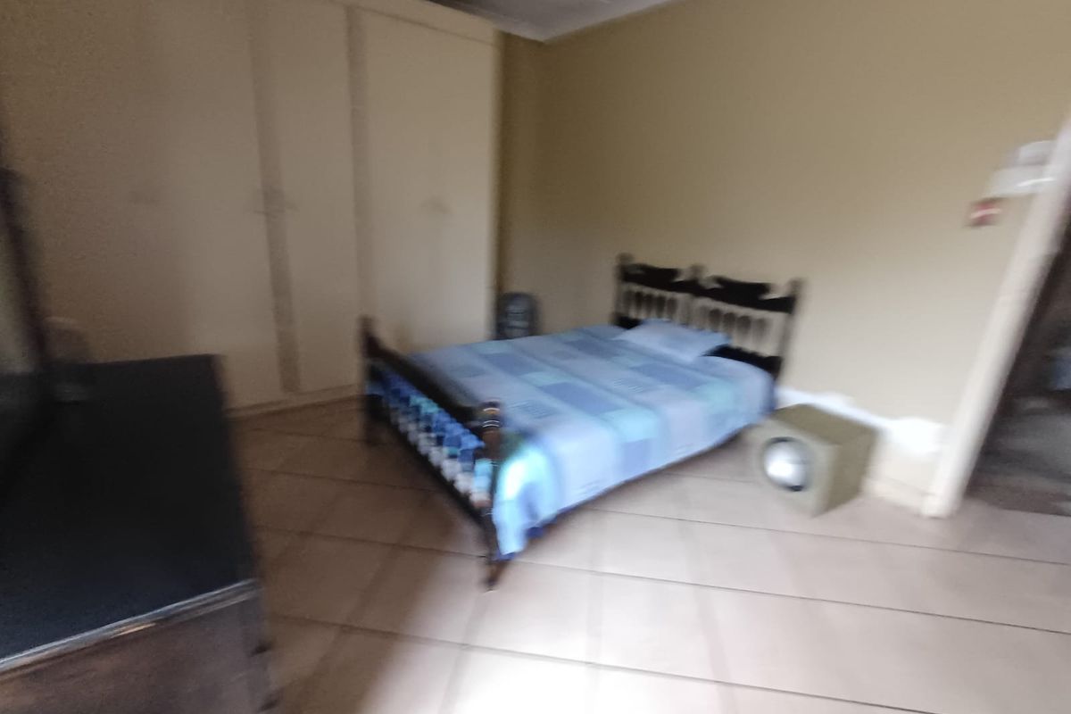 A bedroom featuring tiled flooring and built-in cupboards.
