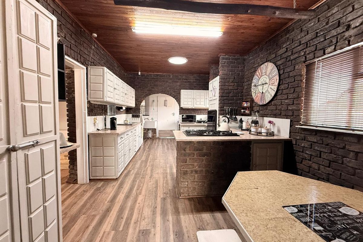 Rustic kitchen featuring exposed brick walls, timber-paneled ceiling, built-in cabinetry, and a central brick-based island with a gas hob.