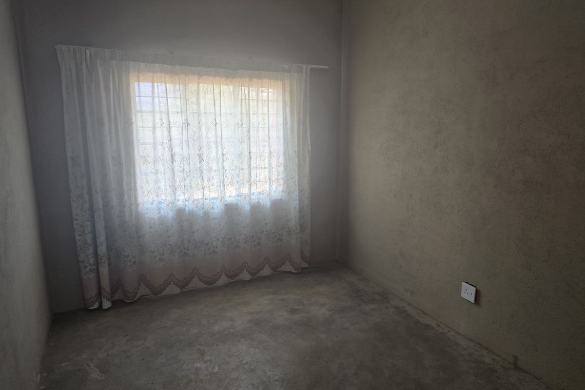 A simple, unfinished bedroom featuring raw concrete flooring and unpainted plaster walls, providing a blank canvas for future renovation and interior design.