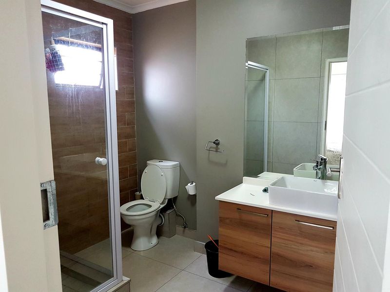 Modern bathroom featuring a glass-enclosed shower, a contemporary vessel sink vanity, and neutral wall tiling.