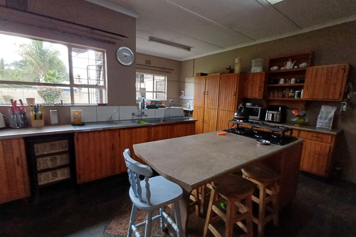 Spacious kitchen featuring wooden cabinetry, a central island with a built-in hob, and ample natural light from large windows.