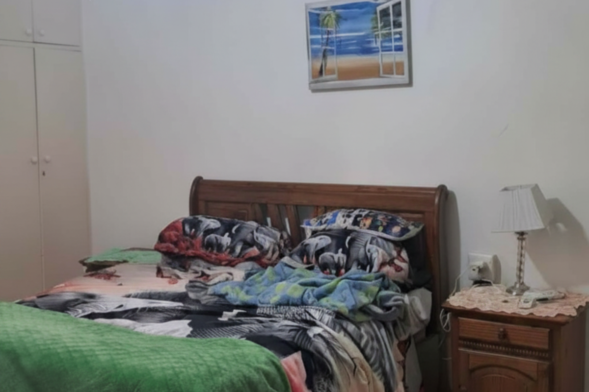 A bedroom featuring tiled flooring, built-in cupboards, a ceiling fan, and a wall-mounted air conditioning unit.