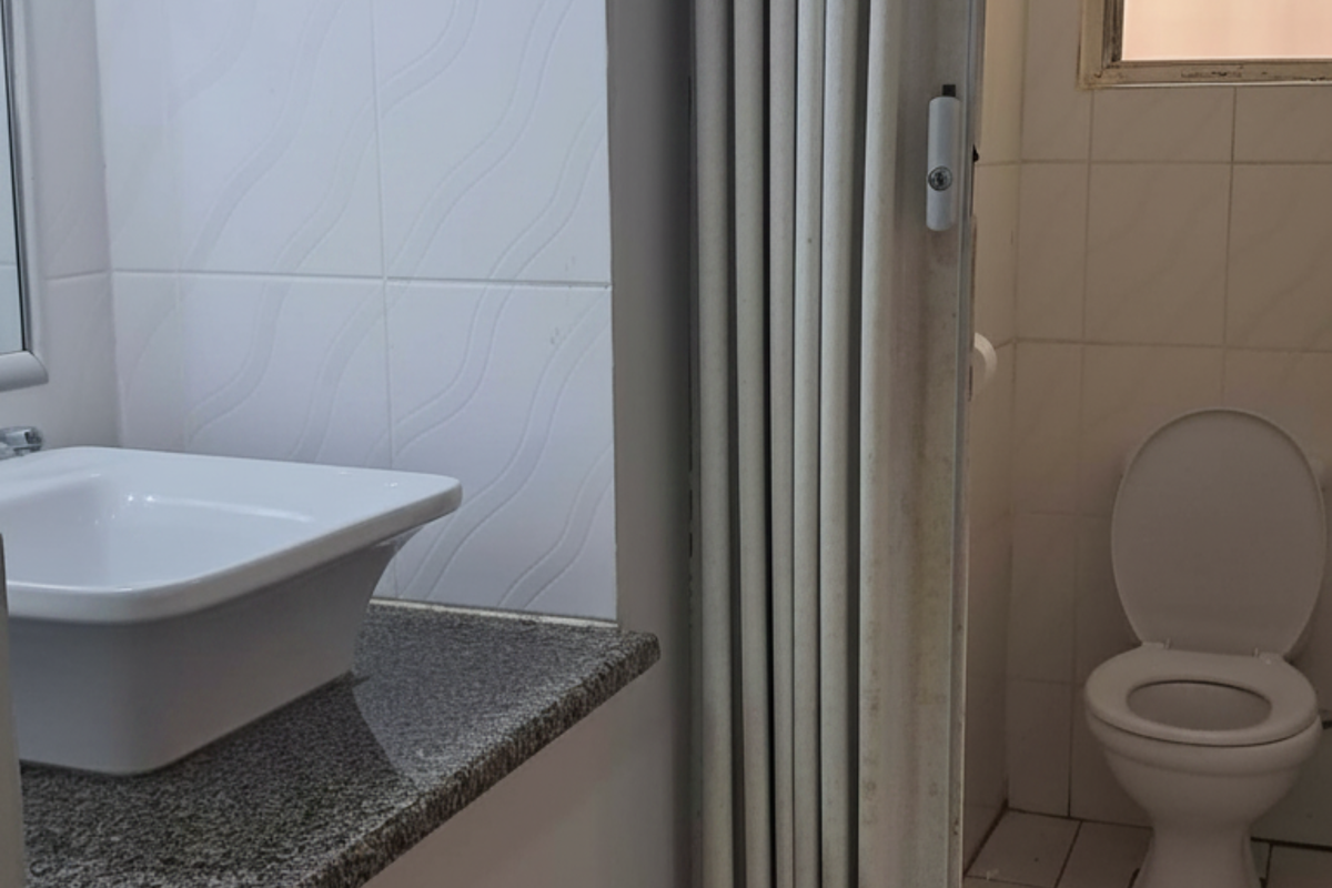 A functional bathroom featuring a vanity with a granite countertop, a vessel sink, and a separate toilet area enclosed by a folding door.