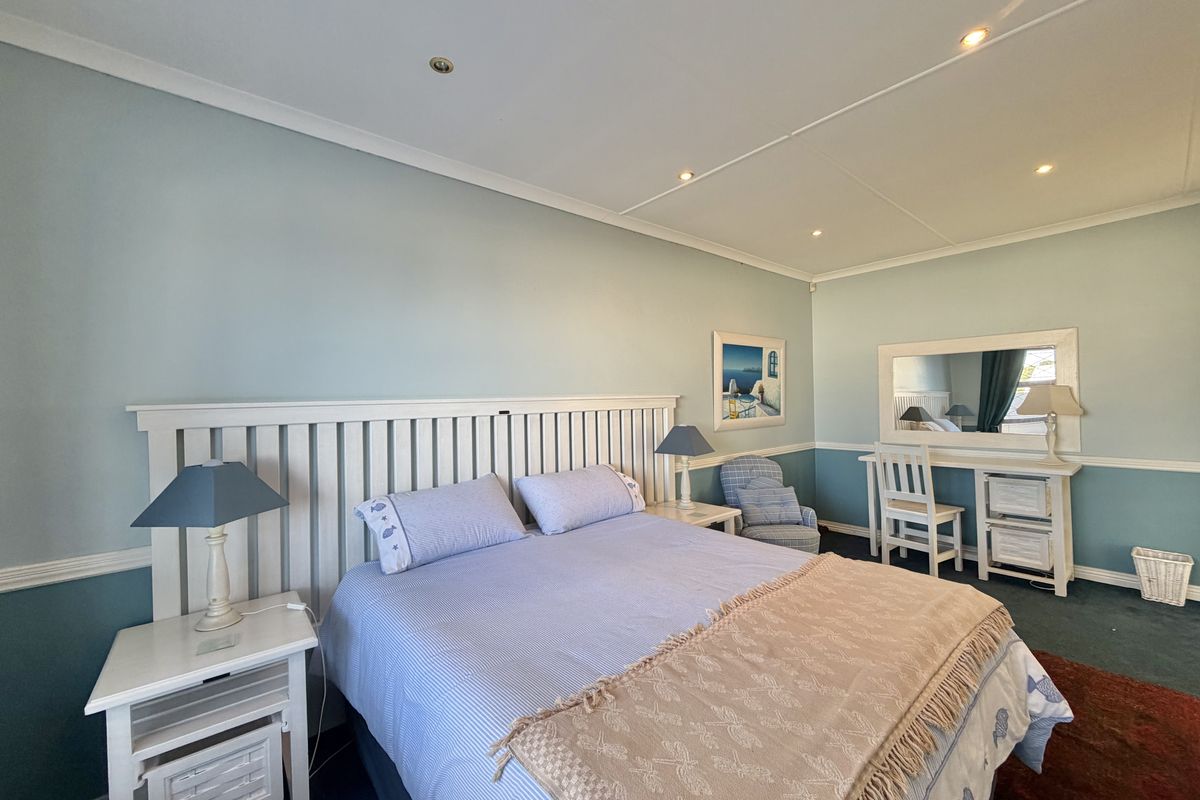A well-lit bedroom featuring recessed ceiling lighting, chair rail molding, and a neutral color palette, providing a comfortable and functional living space.