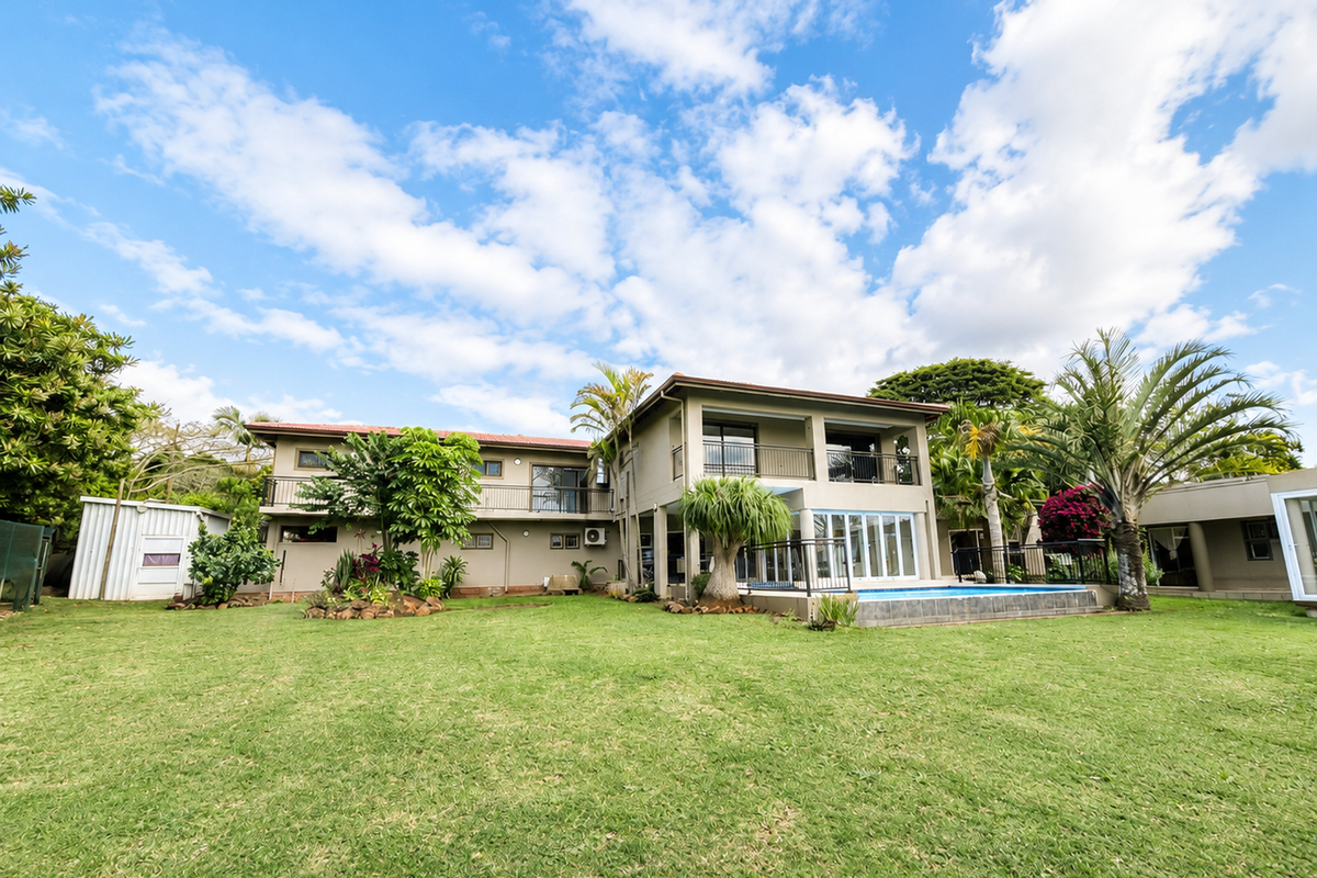 Spacious rear exterior view of a two-story house featuring a swimming pool, landscaped garden, and upper-level balconies.