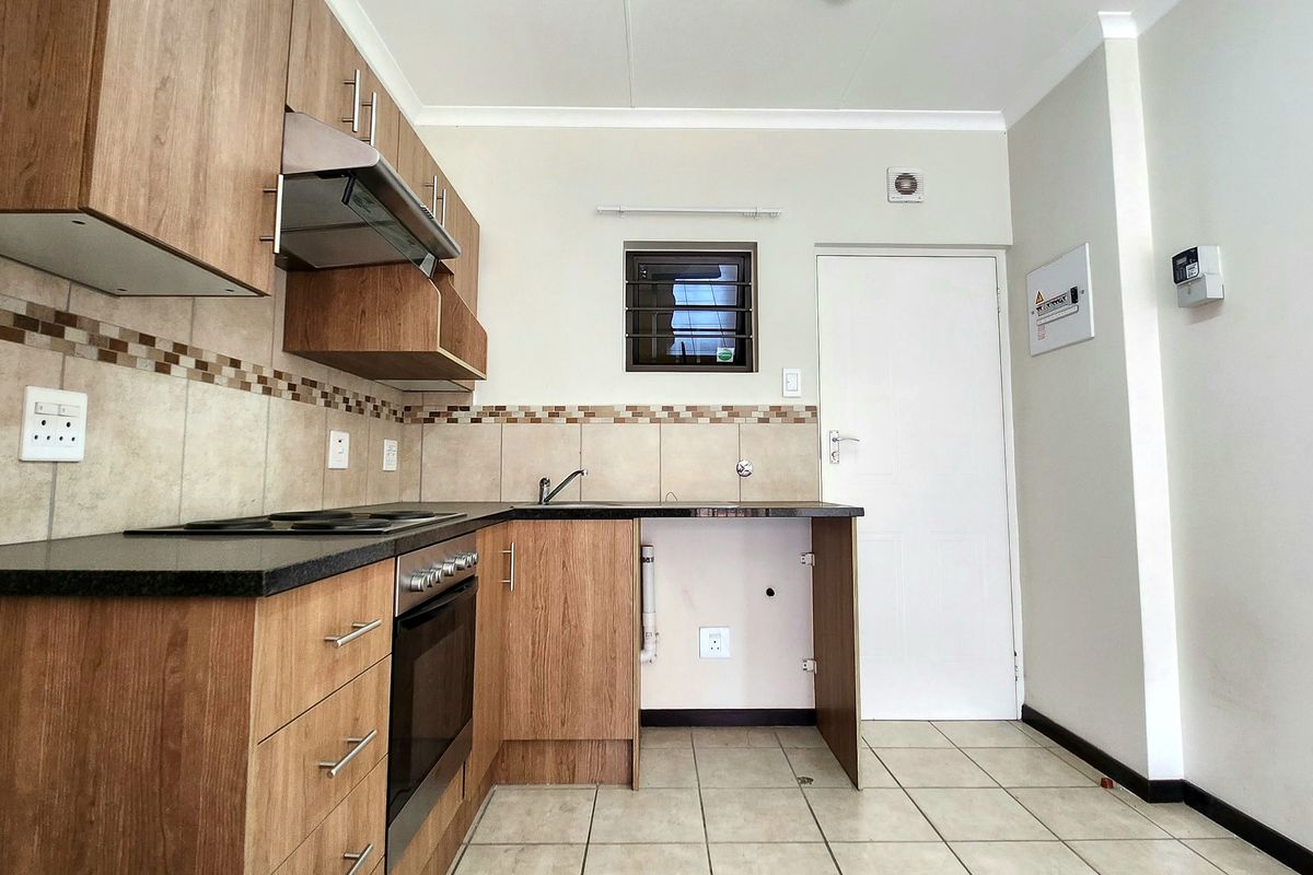 A functional kitchen featuring wood-look cabinetry, dark countertops, built-in oven and hob, tiled backsplash, and tiled flooring.