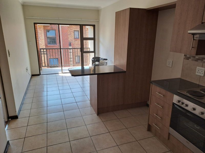 Open-plan kitchen and living area featuring built-in cabinetry, granite countertops, and direct access to a balcony through a sliding glass door.