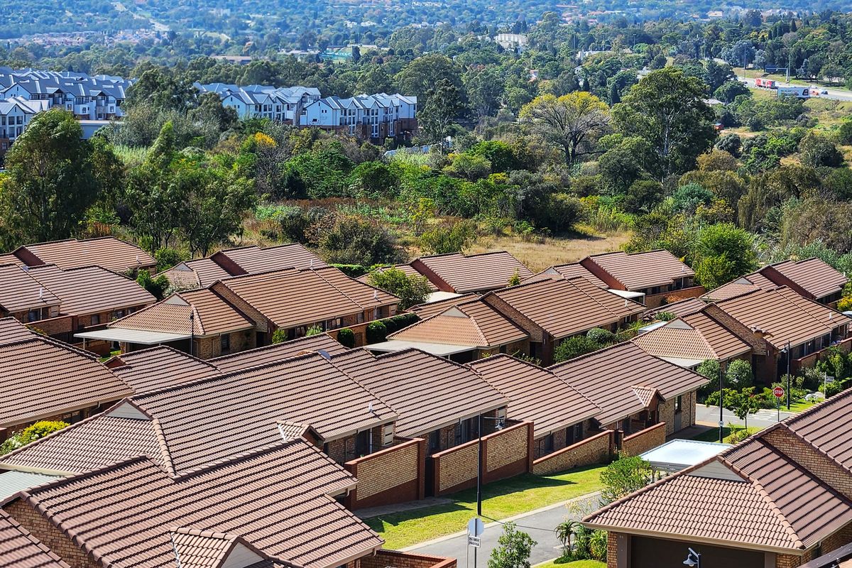 An elevated aerial view of a residential apartment complex featuring uniform tiled roofs and brick exterior finishes within a landscaped estate setting.
