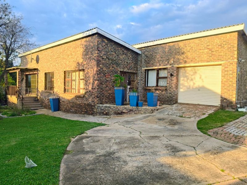 Front exterior view of a single-story brick house featuring a paved driveway, attached garage, and a small front garden area.