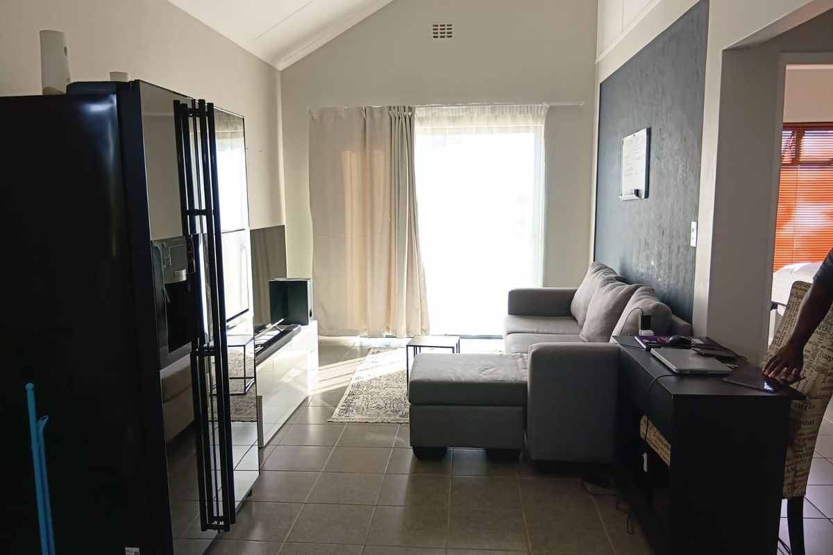 A living room featuring high vaulted ceilings, tiled flooring, and a sliding glass door providing natural light and access to the exterior.