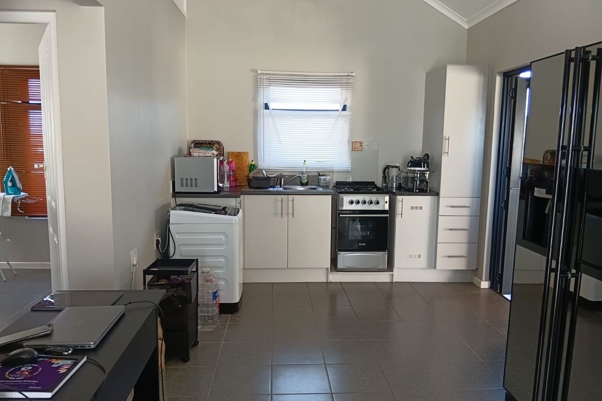 A functional kitchen featuring tiled flooring, built-in cabinetry, a gas stove with oven, and a stainless steel sink.