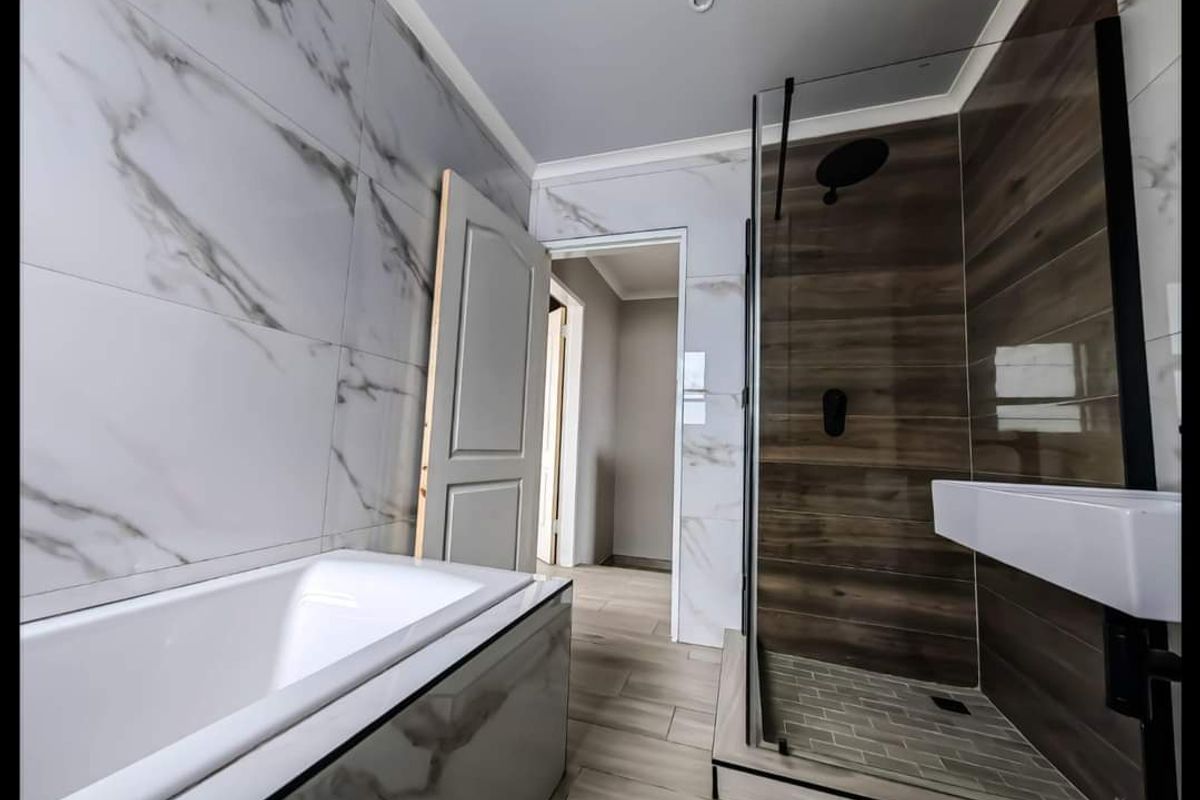 Modern bathroom featuring a sleek bathtub, a walk-in shower with wood-look tiling, and contemporary marble-effect wall tiles.