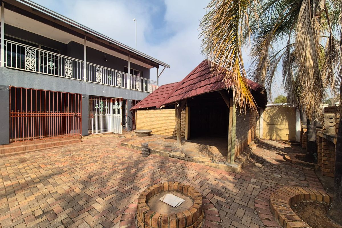 Rear courtyard featuring a paved patio area, a covered gazebo structure, and a brick-built fire pit, providing a functional outdoor entertainment space.