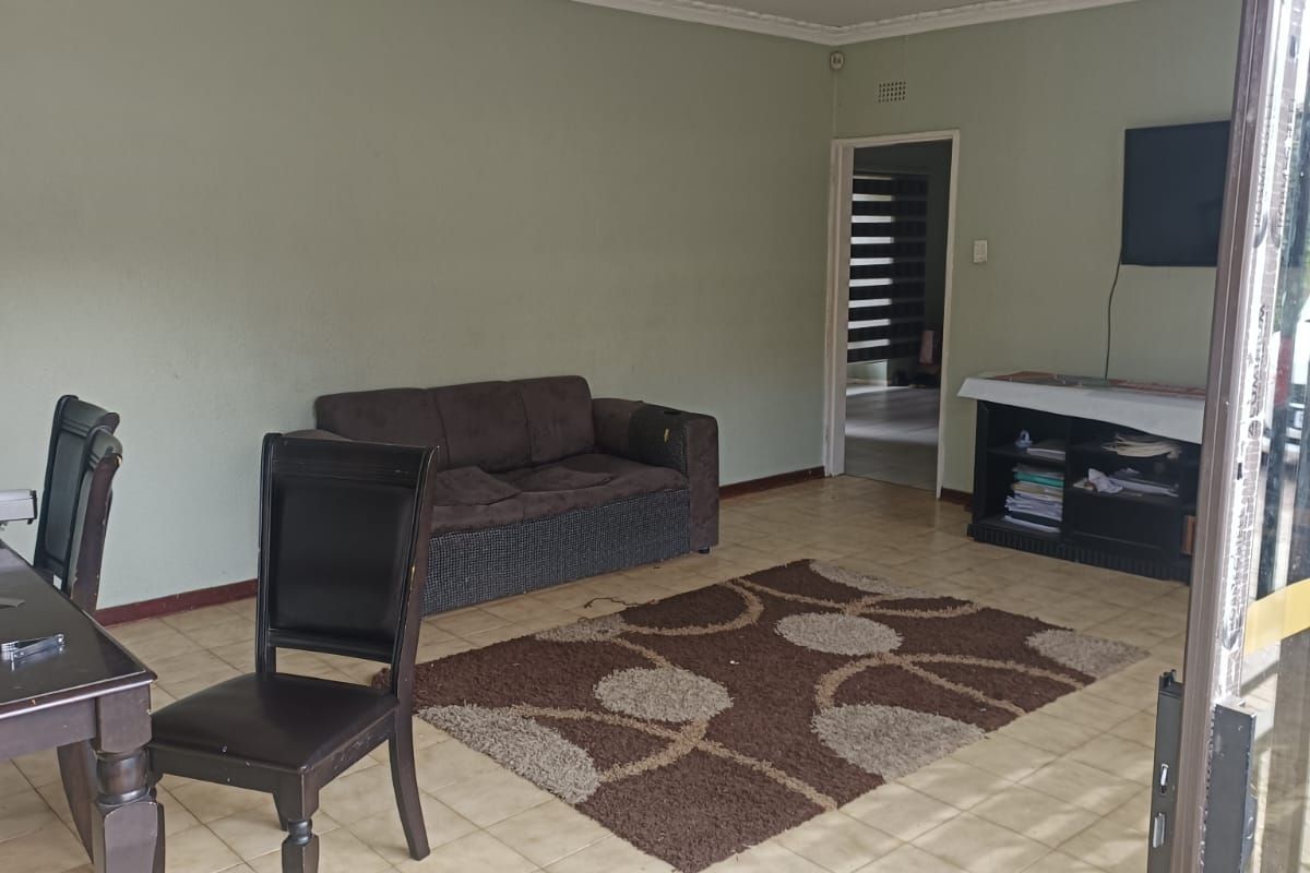 A living room featuring ceramic floor tiles, coved ceiling cornices, and access to the exterior via a sliding glass door.