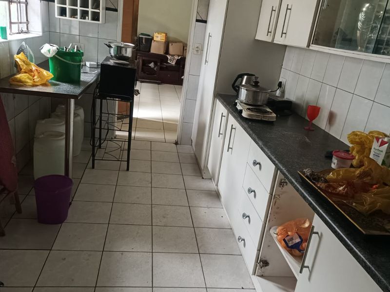 A functional kitchen featuring tiled flooring, white cabinetry, and a dedicated wine rack, currently showing signs of wear and requiring cosmetic updates.