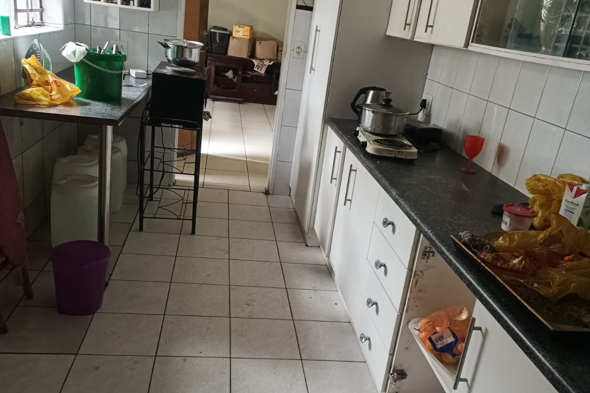 A functional kitchen featuring tiled flooring, white cabinetry, and a dedicated wine rack, currently showing signs of wear and requiring cosmetic updates.
